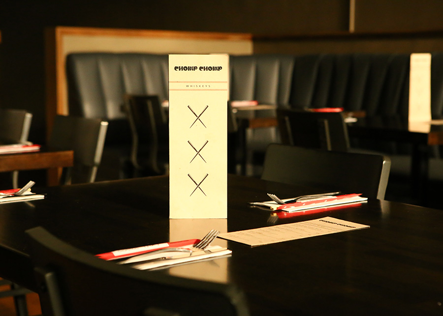 The glossy black tables on the dining floor, upon each a drink menu stands between the silverware